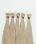 Blonde raw hair extension bundles with keratin tips from Prolonged Hair on white background