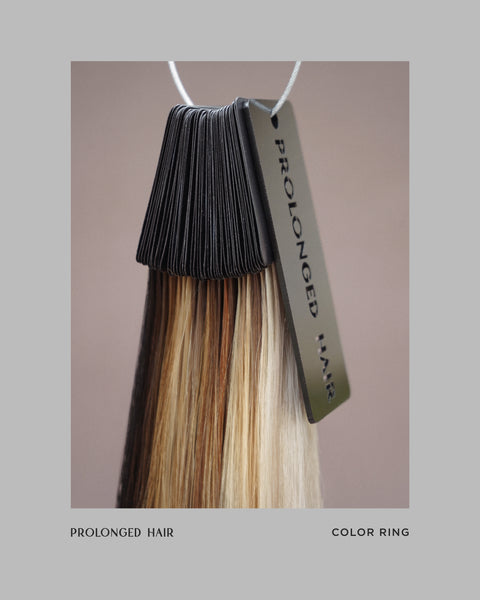 Color ring with brown, blonde, and black hair extensions hanging on a hook against a beige background.